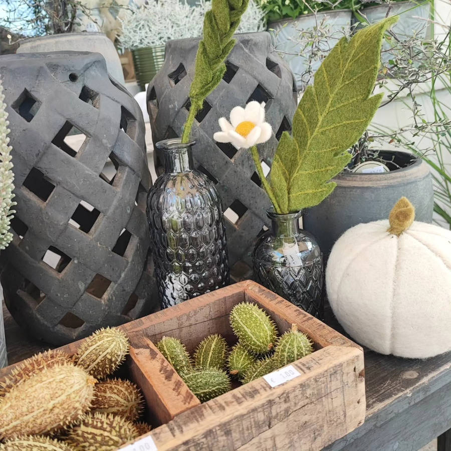 Brautstrauß mit Rosen, Chrysanthemen, Beeren und Trockenblumen in warmen Farbtönen, gehalten von einer Hand mit gestreiftem Ärmel