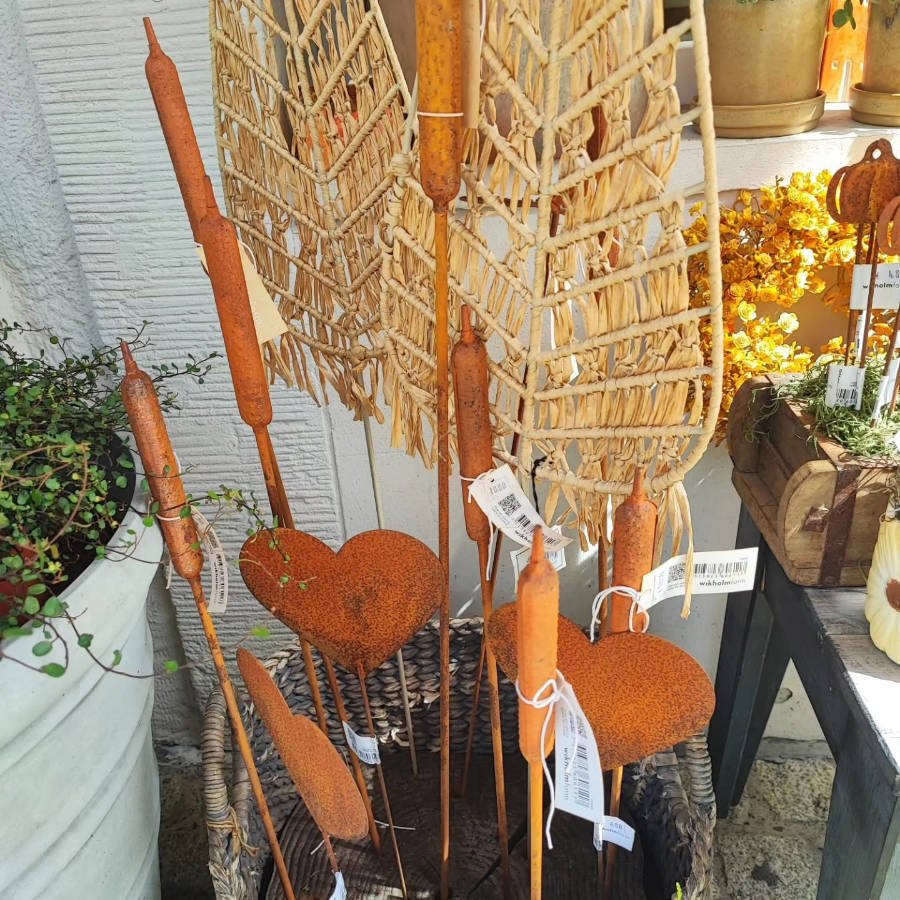 Bunter Blumenstrauß mit verschiedenen Blüten und grünen Blättern, gehalten von einer Hand vor einer Holzwand